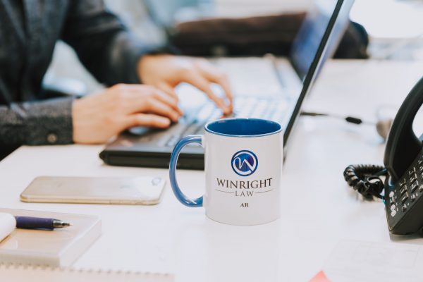 Blue and White Winright Law coffe cup sitting on a desk.